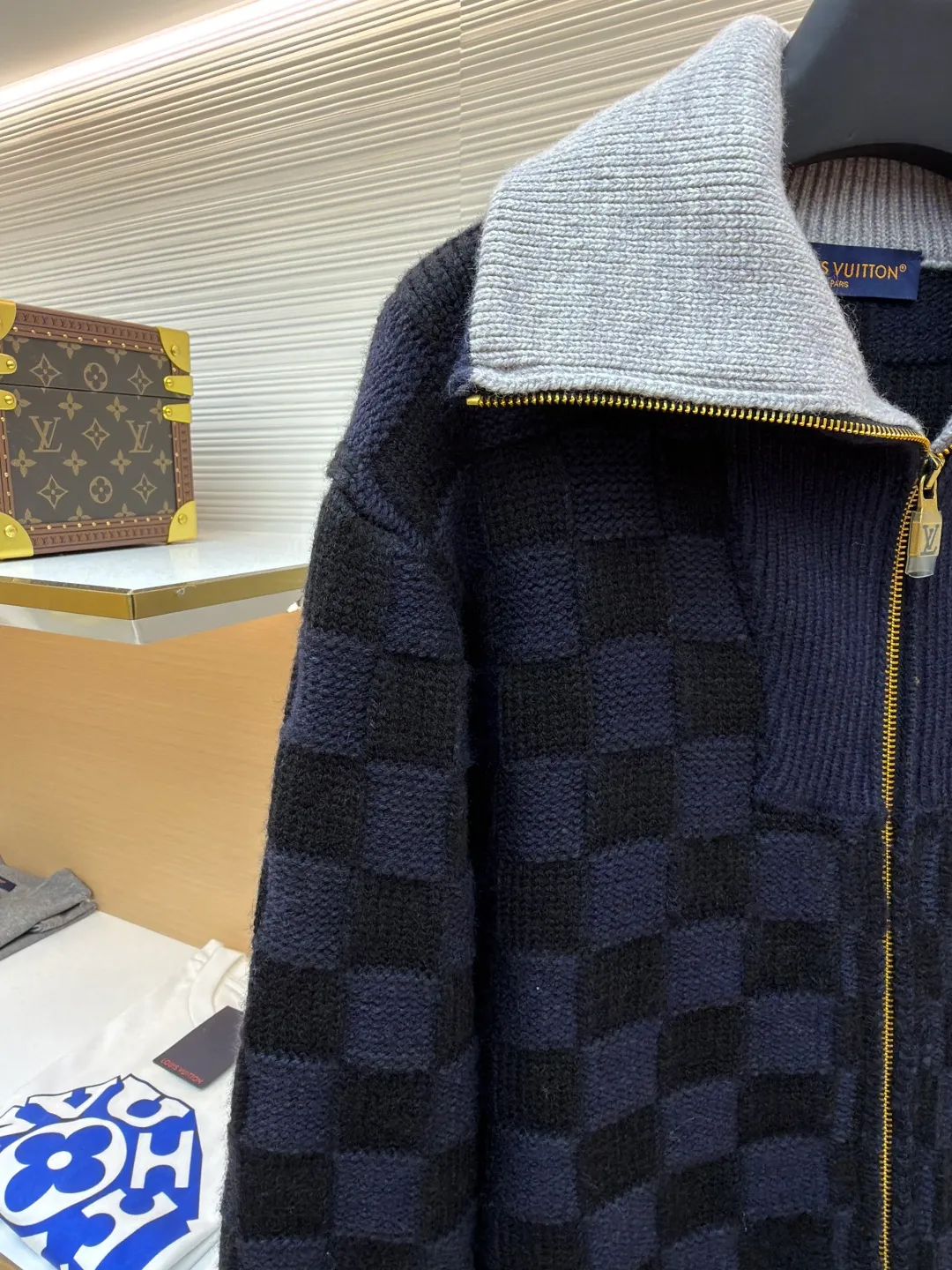 LOUIS VUITTON knitted waist contrast ribbed collar sweater ●Original version: purchased and developed by 20433 ●Item number: 1682136-C10 ●Fabric: wool blended fabric ●Technology: knitted ●Color: black and blue ●Version: fitted version ●Weight: about 1360 grams ●Size: S-M-L-XL ●Description: This Louis Vuitton checkerboard knitted zipper jacket is made of double-ply merino wool blended yarn and is woven with a 12-needle three-dimensional knitting process on a German Stoll computerized flat knitting machine. The Damier checkerboard pattern on the body uses intarsia knitting techniques, and the layered interweaving of dark blue and black yarns creates a 3D concave and convex texture. There is no printed patchwork process, and the pattern and the body are integrated for a more textured look. The neckline is designed with contrasting ribbed lapels, and built-in spandex elastic yarn improves resilience; the metal zipper is made of gold-plated brass, and the teeth are precision polished. The zipper track and the seam of the body are sewn with overlock stitching, and the stitch length is controlled within 0.2cm. The contrasting ribbed edges on the cuffs and hem are pre-shrunk and hand-shaped and ironed, making the garment crisp and less likely to loosen after long-wearing. Every detail demonstrates the brand's strict standards of high-end knitting technology. The overall wiring is straight and delicate, the fabric is comfortable and soft, and the color is consistent without color difference. It can be matched with the same style to create a fashionable look and control various occasions. Customized accessories, complete with three standards, same style for men and women!